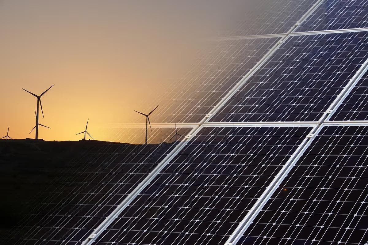 Nahaufnahme eines Photovoltaik-Moduls kombiniert mit Windturbinen im Hintergrund