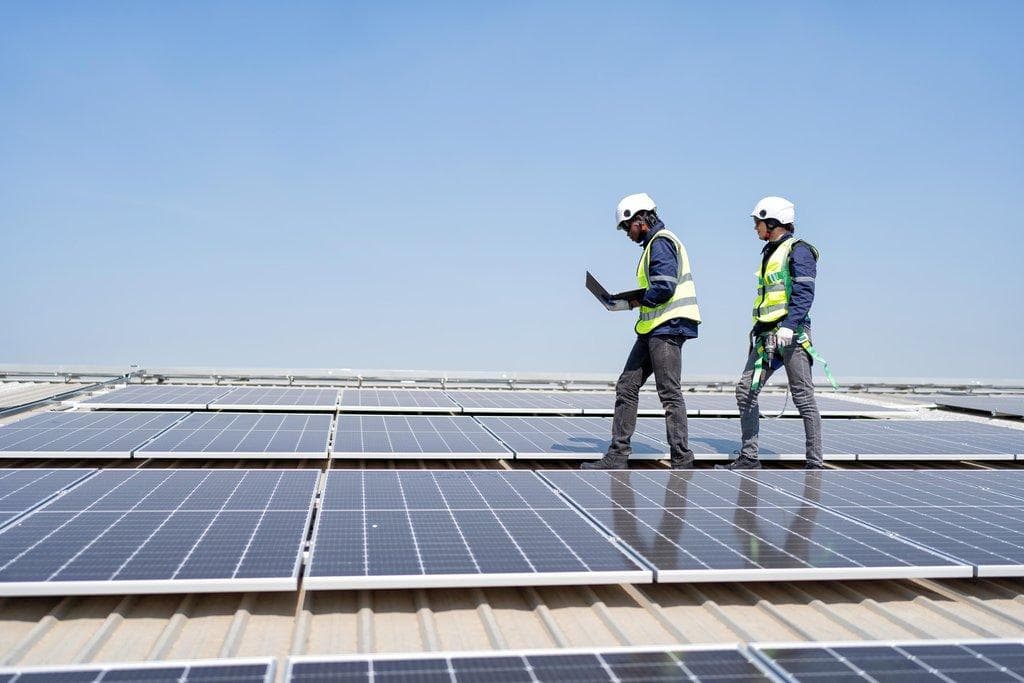 Ingenieur steht auf Dach neben Solarpanels