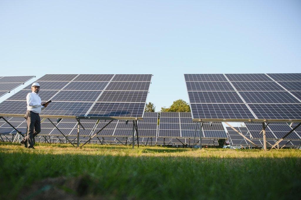 Mann steht neben Solarpanels auf Solar-Kraftwerk
