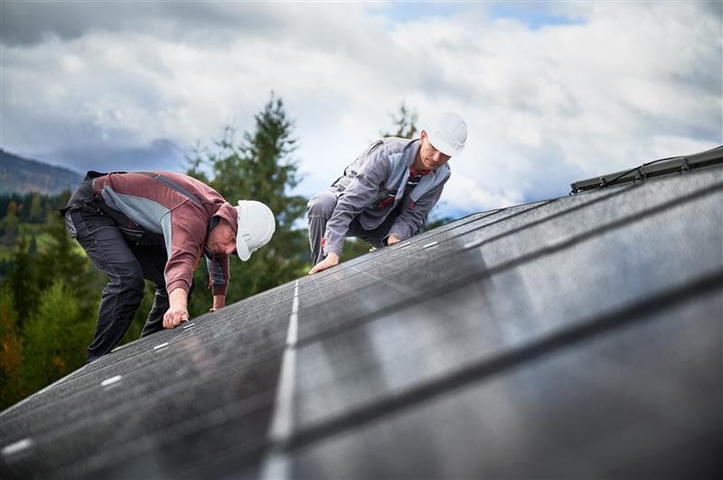 Techniker installieren Photovoltaik-Solarmodule auf Hausdach