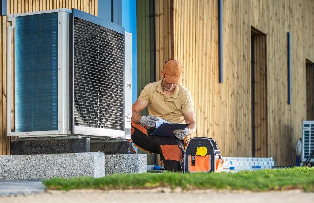 Arbeiter installiert moderne Wärmepumpe am Gebäude